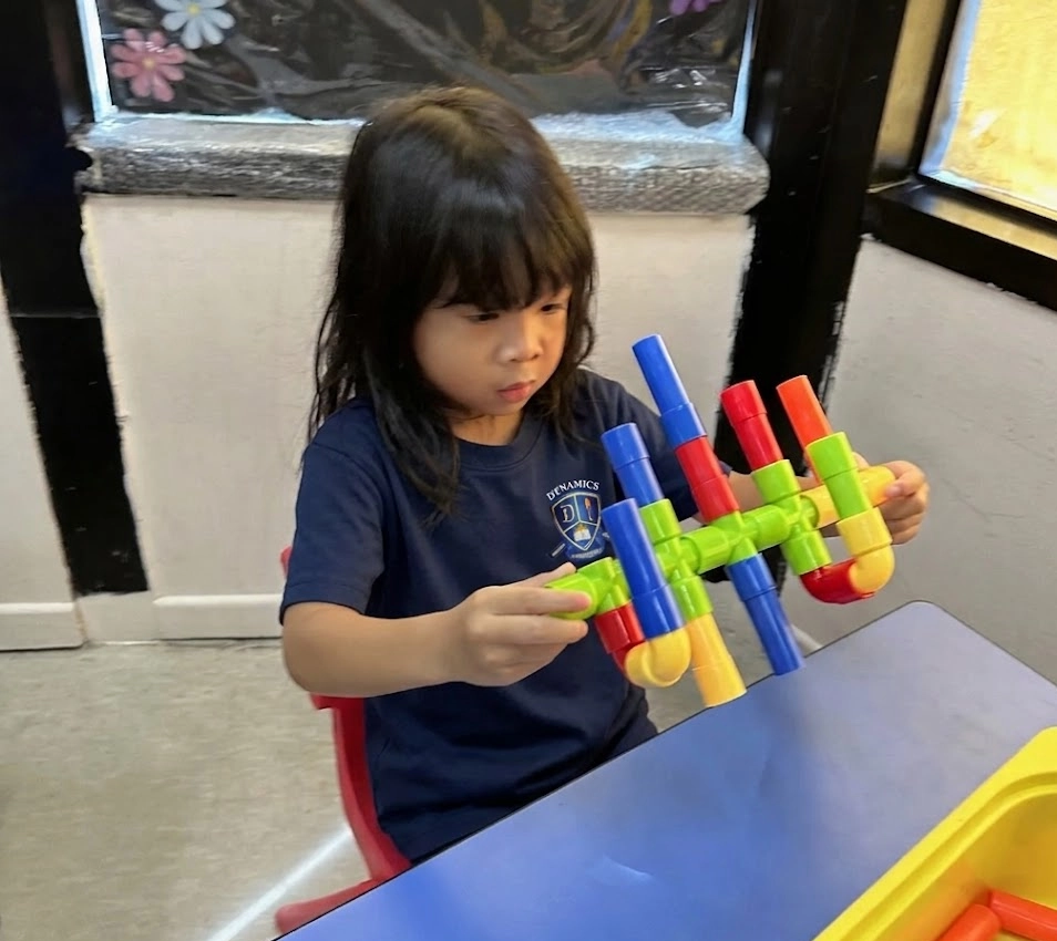 Therapist supporting a child with a fine motor activity in a bright, welcoming therapy room.
